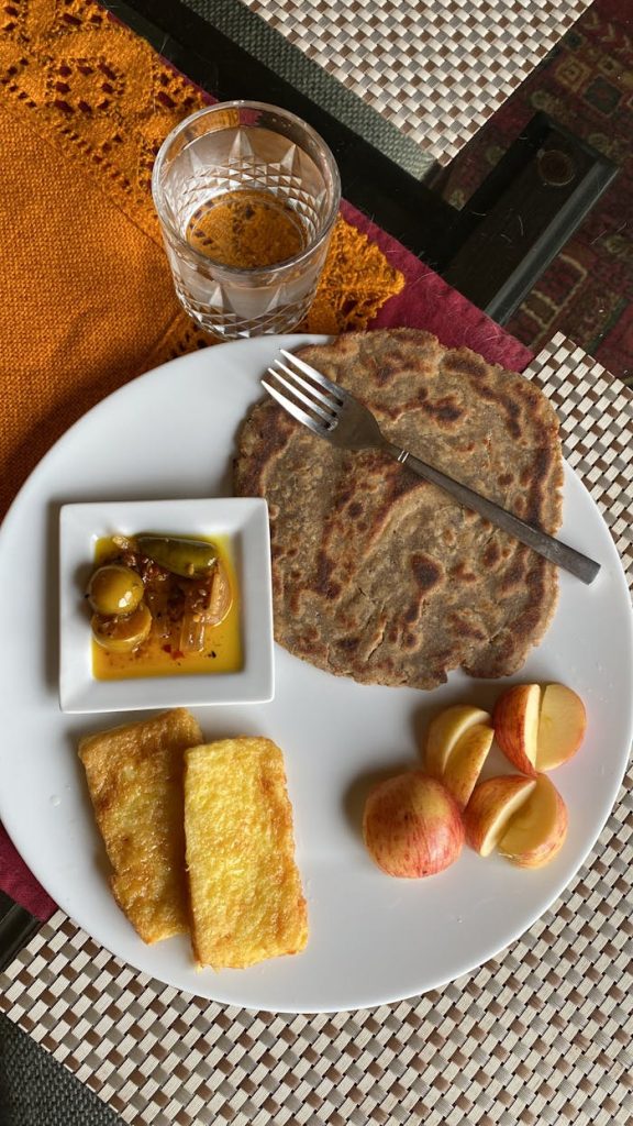 Top view of a healthy breakfast featuring paratha, fruit, and beverage on a stylish table setting.